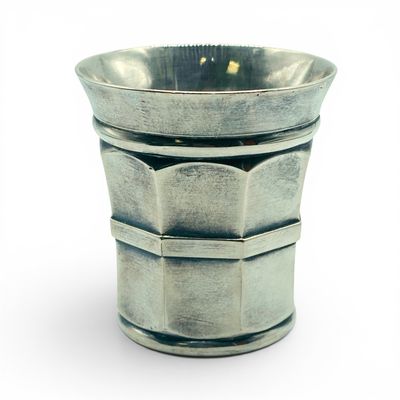 une tasse en argent posée sur une surface blanche