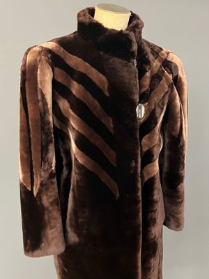 une photo d'un manteau marron et noir posé sur un présentoir pour mannequin