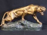 bronze sculpture of a lion on a rock on a black background