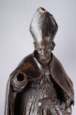 statue d'un homme coiffé d'un chapeau et vêtu d'une robe, tenant un chien dans ses bras