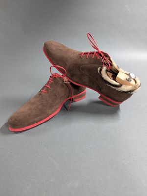 a pair of brown sued shoes with red laces on them