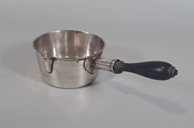 une tasse en argent avec une anse noire posée sur une table blanche