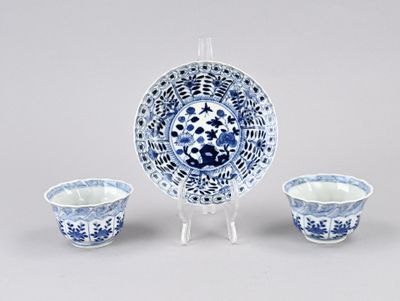 une assiette bleue et blanche et deux bols posés sur un support