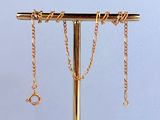 un collier en or posé sur un support, avec des chaînes qui en pendent