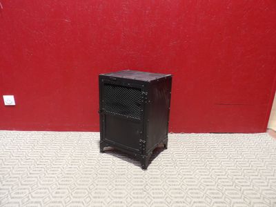 une petite armoire noire posée au sol devant un mur rouge