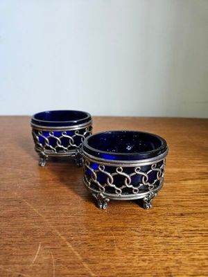 une paire de bols en verre bleus ornés de chaînes, posés sur une table en bois