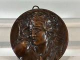 a bronze plaque of a woman holding a cat