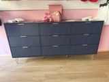 une commode bleue aux pieds dorés dans une chambre rose