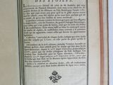 an open book on a white table with a flower on it