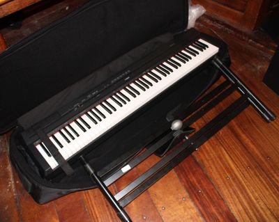 une mallette noire contenant un clavier, posée sur un plancher en bois