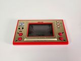 an image of a red and gold game console sitting on top of a white table