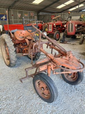 a rusted out tractor in a garage with other tractors