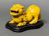 yellow statue of a lion on a black base on a gray surface