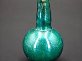 a green glass vase sitting on a black surface
