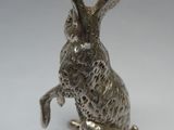 un gros plan d'une figurine de lapin en argent posée sur une surface blanche