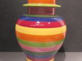 un vase multicolore muni d'un couvercle, posé sur une table