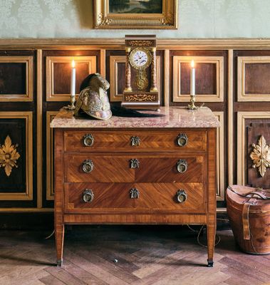 une commode sur laquelle est posée une horloge, dans une pièce