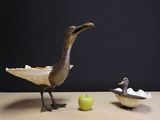 a bird that is standing next to an apple on a table