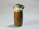 un vase brun et noir posé sur une surface blanche