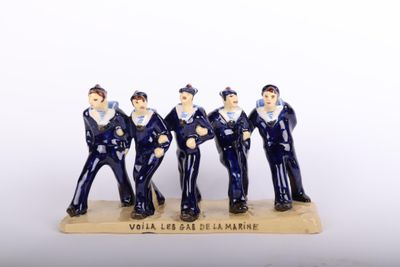 three figurines of men dressed in navy uniforms stand on a wooden base