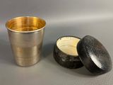 a silver cup next to a silver container on a table