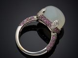 a white jade and pink sapphire ring on a black surface