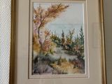 framed watercolor painting of a landscape with trees and a river