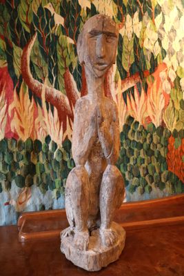 une statue représentant un homme assis sur une table devant un tableau