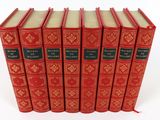 six red books lined up in a row on a white surface