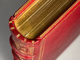 close up of a red book with gold binding on a white surface