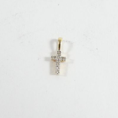 un gros plan d'un pendentif en forme de croix en diamant posé sur une surface blanche