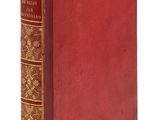 un vieux livre à la couverture rouge posé sur une surface blanche