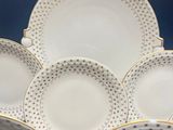 six white and gold dinner plates with polka dots on them