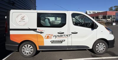 une camionnette blanche garée sur un parking à côté d'un bâtiment