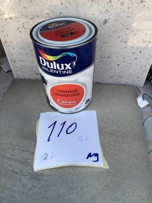 un gros plan sur un pot de peinture et un bout de papier posé par terre