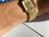 a woman ' s wrist with a gold watch and blue beads