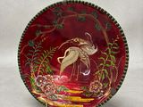 a red plate with a bird on it on a white background