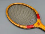 une raquette de tennis en bois avec un manche rouge sur un fond gris