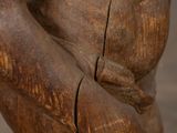 carved wooden statue of a man holding a knife in his right hand