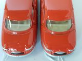 two red toy cars sitting side by side on a white surface