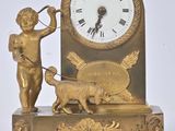 a gold clock with an angel and a dog on it