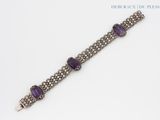 a close up of a bracelet with purple stones on it