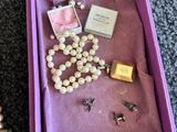 une boîte violette ouverte, remplie de perles et d'un collier