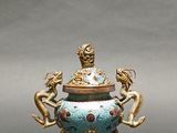 a blue and gold vase with a statue on it