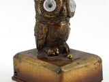 une statue de chouette en bronze posée sur un bloc de bois