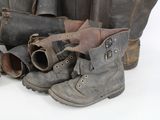 many pairs of boots and a bag sitting on the floor