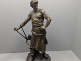 statue en bronze représentant un homme muni d'une canne et coiffé d'un chapeau, posée sur un socle en marbre