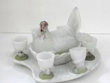 un poulet blanc posé sur un plateau avec des tasses et des soucoupes