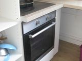 a small kitchen with a stove, sink, and shelves