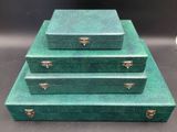 three green suitcases stacked on top of each other on a table